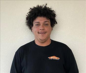 Male employee with curly hair smiling in front of a white background