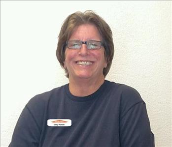 Female office employee with brown hair smiling in front of a white background