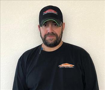 Male employee wearing a hat standing in front of a white background