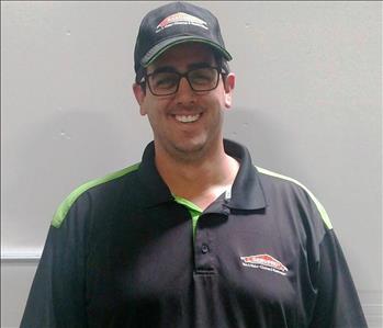 Male employee wearing a hat smiling in front of white background